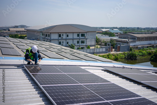 Blue collar worker is inspecting solar panel at rooftop of factory.