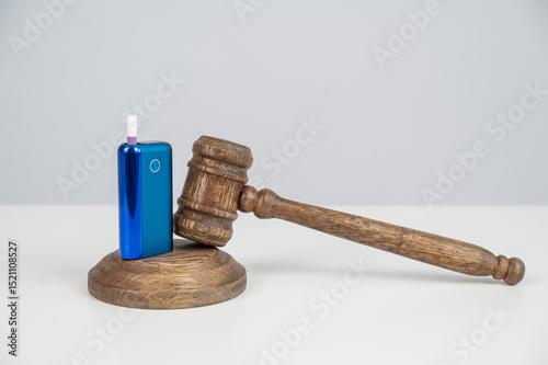 Judge's gavel hits e-cigarette. Smoking ban. Tobacco heating systems. 
