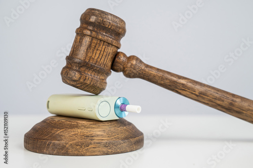 Judge's gavel hits e-cigarette. Smoking ban. Tobacco heating systems. 