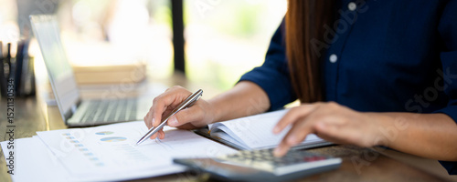 Woman holding pen pointing on paper using calculator for business financial accounting calculate money bank loan rent payments manage expenses finances taxes doing paperwork concept, close up view.