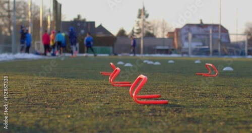 Athletes are engaged in training on a sports field, featuring agility cones positioned in the foreground