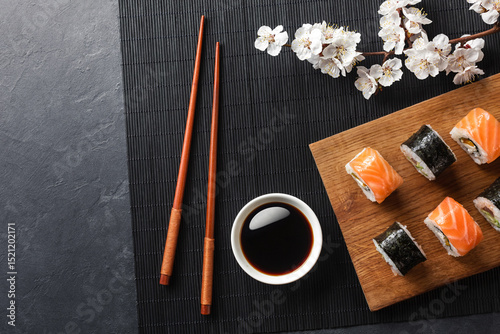 Set of sushi and maki rolls with branch of white flowers on stone table photo