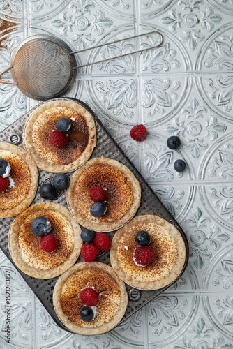 Cream cheese tartlets or mini pies with cacao espresso powder and fresh raspberries and blueberries.