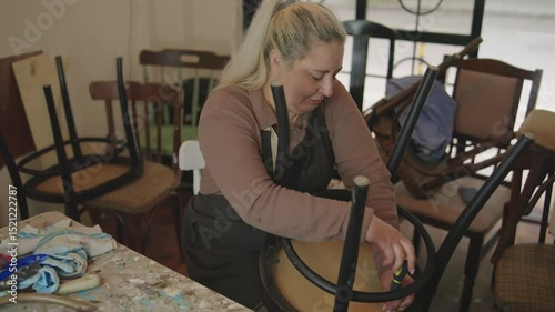 Young woman Dismantling antique chair for restoration. Small garage business