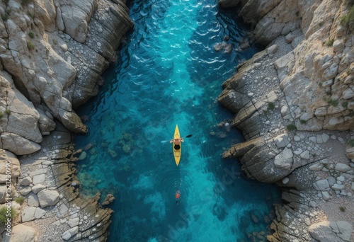 Toma aérea que captura un kayak navegando en aguas turquesas cristalinas a través de estrechos acantilados costeros rocosos