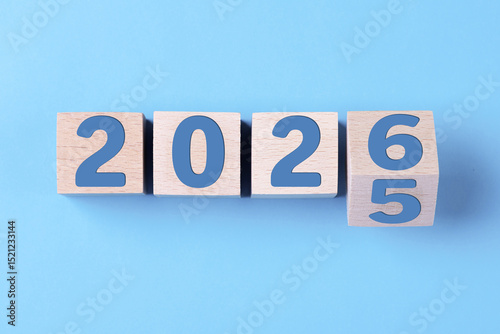 2026 Happy New Year. Wooden cube block change from 2025 to 2026 on blue. Concept 2026 New Year background. Business, resolutions, goals, inspiration, success, ideas