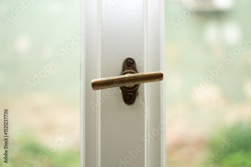 Close-up of an old window with a bronze handle for opening