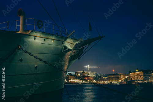 A ship at anchor with a city in the background