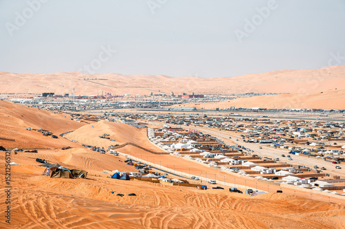 lively Liwa Festival in Abu Dhabi's desert. You can see vibrant tents and vehicles set against wide, rolling sand dunes under a big sky