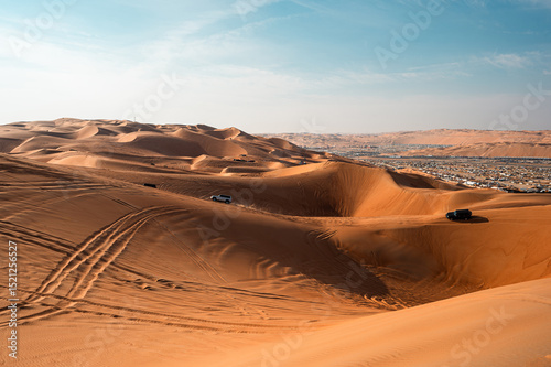Fototapeta Naklejka Na Ścianę i Meble -  golden sand dunes of the Liwa Festival desert in Abu Dhabi. Tracks in the sand lead to a distant encampment, blending festival energy with serene desert beauty