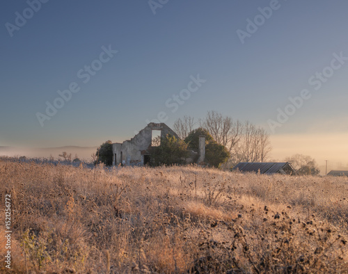A broken down building in a frosty field under a blue sky photo