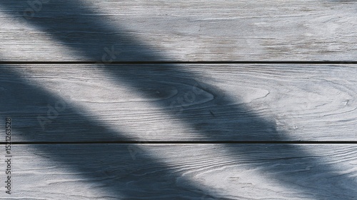 Detailed close-up of grey wood plank texture under sunlight, highlighting natural shadows and grain patterns.