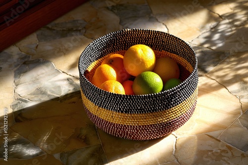 A sunlit basket of fresh citrus fruits on a kitchen counter with rich textures
