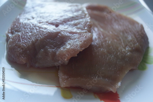 A raw slice of veal, fresh and tender, showcasing a delicate pink hue and finely marbled texture. 
