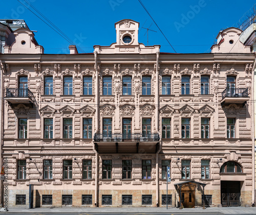 Facade of an ancient building with a iron forged balcony and stucco above the windows.	
