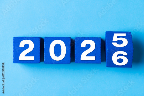 2026 Happy New Year. Wooden cube block change from 2025 to 2026 on blue. Concept 2026 New Year background. Business, resolutions, goals, inspiration, success, ideas