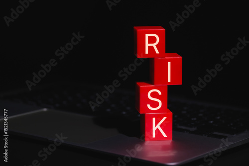 Red Risk Blocks Representing Digital Danger. Stacked red blocks spelling the word RISK placed on laptop, symbolizing digital threats, business uncertainty, data, and cybersecurity concerns.