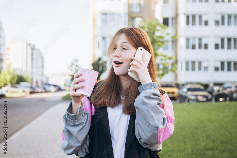 Teenage girl with a cup of coffee emotionally talking on the phone in the city. Teenage girl with a cup of coffee emotionally talking on the phone in the city.