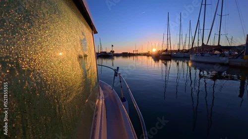 Sunrise light on a wet dew covered boat window at the marina