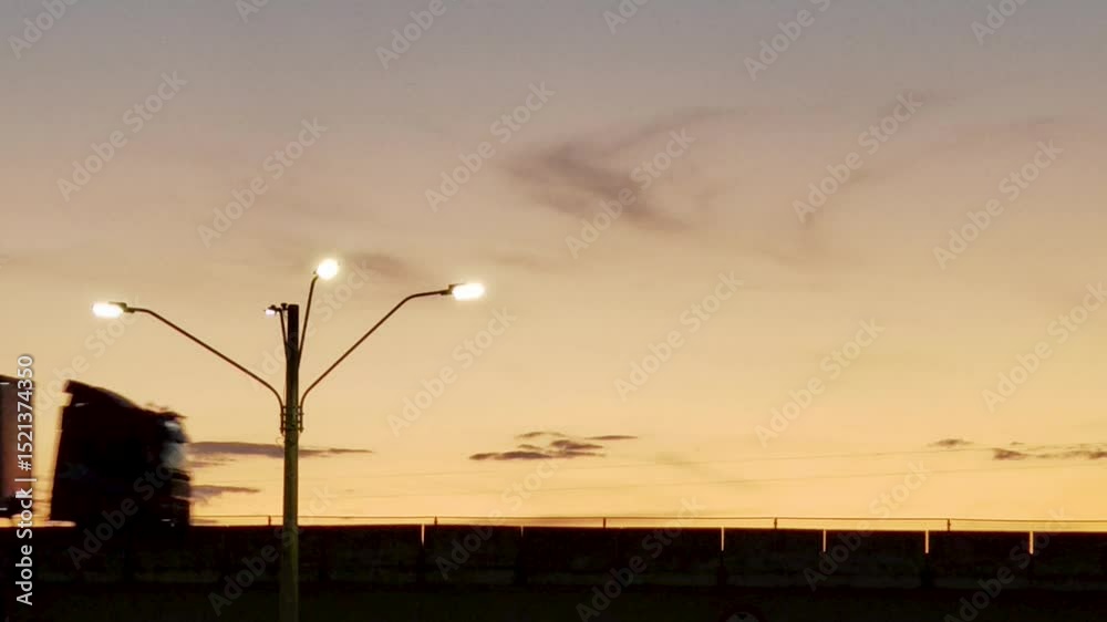 Silhueta de rodovia movimentada. Veículos em movimento ao pôr do sol.