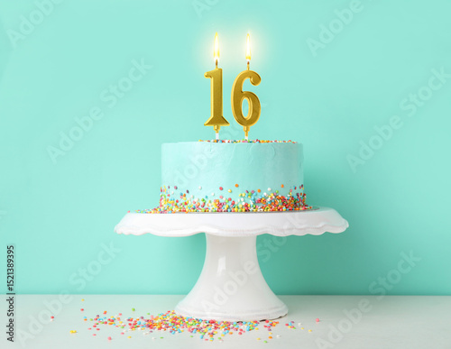 Photography Yummy cake with burning number shaped candles and sprinkles on white table against turquoise background