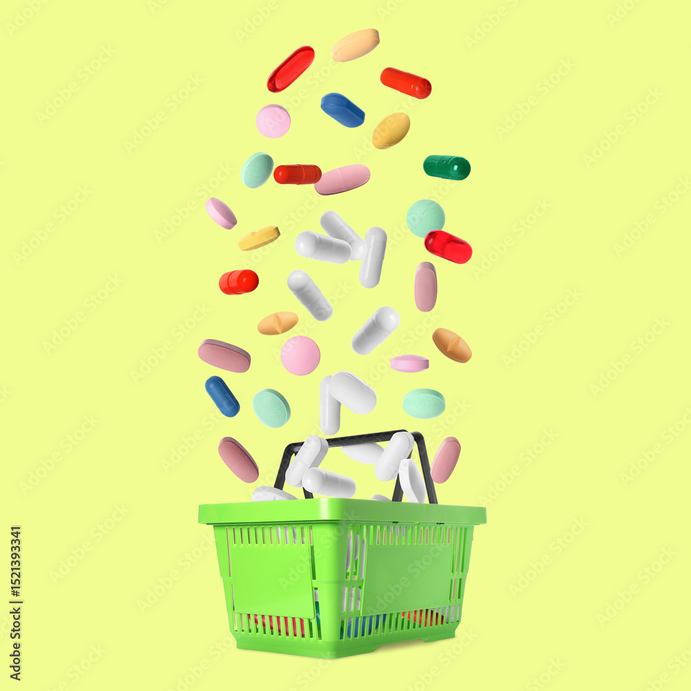Fototapeta premium Different pills falling into shopping basket on pale yellow background