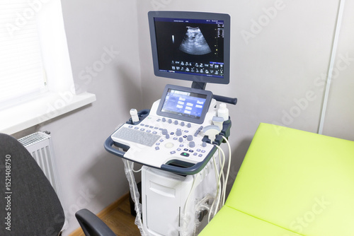A modern ultrasound machine with a screen displaying a scan, an examination chair, and a patient table are in a hospital echo room.