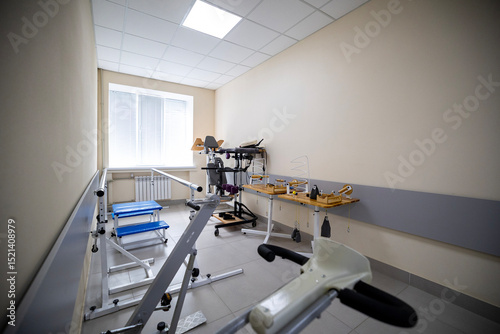 A rehabilitation room features diverse exercise and physical therapy equipment, including a gait training machine, a treadmill, a stationary bicycle, manipulative tools, designed for patient recovery.