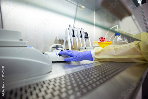 Equipment for DNA/RNA extraction, including pipettes and a shaker, is inside a ventilated safety cabinet in a laboratory