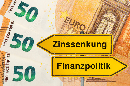 Wallpaper Mural Zwei Wegweiser zeigen in unterschiedliche Richtungen und sind beschriftet mit dem Aufdruck Zinssenkung und Finanzpolitik vor viel Euro Banknoten - FOTOMONTAGE Torontodigital.ca