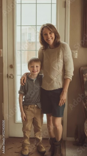 Smiling woman standing with her young son near a door wearing casual clothing indoors in an entryway, home portrait