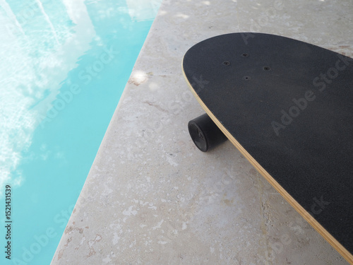 Skateboard next to outdoor swimming pool.