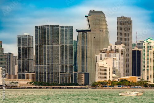 A stunning view of Miami's downtown and bricked district under a clear blue sky. Sleek skyscrapers rise above the water, illustrating the city's dynamic growth and architectural diversity.