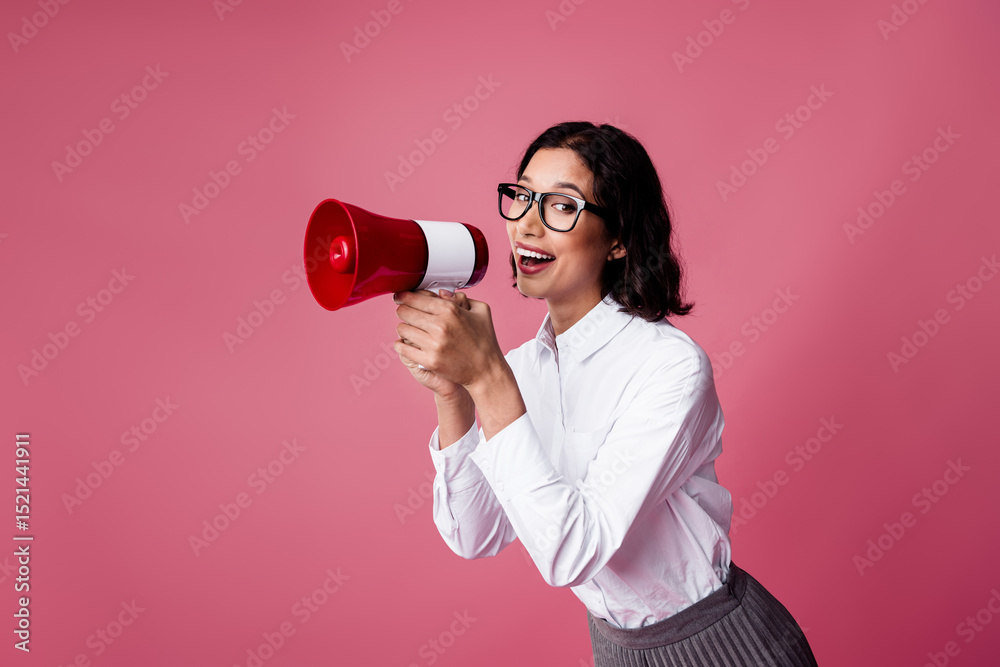 Funny young woman in formal wear holding a megaphone on pink background, promoting ideas with a cheerful and stylish attitude Funny young woman in formal wear holding a megaphone on pink background, promoting ideas with a cheerful and stylish attitude