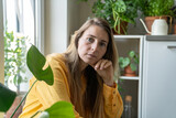 Portrait of thoughtful middle aged woman surrounded by indoor plants, looking at camera. Tired serious blonde female plant lover with green thumb, home gardening passion, botanical enthusiast. 