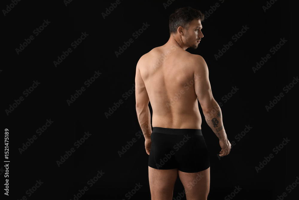 Fototapeta premium Young man in stylish underwear on black background, back view. Space for text