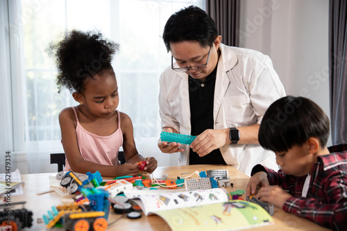 A male adult, possibly an instructor, guides two young children, a girl and a boy, as they diligently work on assembling colorful robotics projects with construction toys