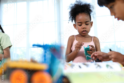 A young girl with dark curly hair is deeply focused on assembling a colorful construction toy, engaging in a hands-on educational activity.