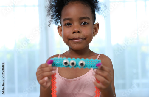 An adorable African-American girl proudly displays her colorful construction toy creation with big eyes, showcasing the joy of hands-on learning and creativity.