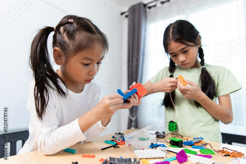 Two young girls are engaged in a STEM activity, building and exploring with colorful robotics kits at a table, fostering hands-on learning.