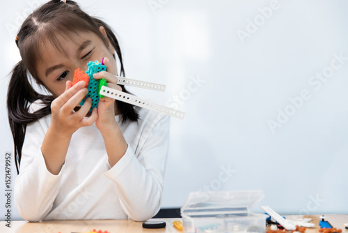 A young girl intently builds a colorful STEM or robotics model, focusing on her educational project, fostering creativity and critical thinking skills