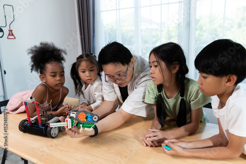 Diverse group of children learning about robotics with a teacher in a STEM class. Hands-on science and technology education in a fun and engaging classroom environment