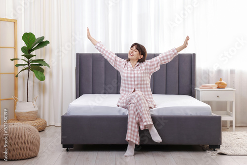 Beautiful woman sitting on soft mattress at home