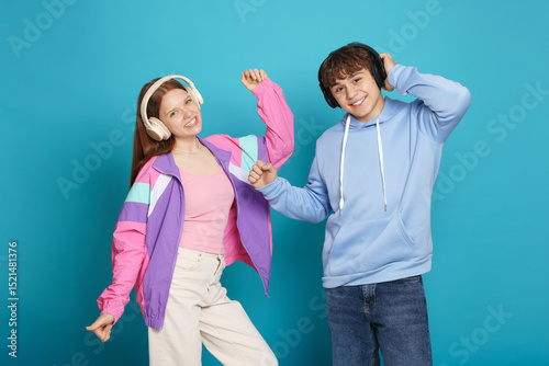 Wallpaper Mural Teenage girl and boy with headphones dancing on light blue background Torontodigital.ca