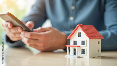 Close-up of men's hands typing on a phone, a model of a private house