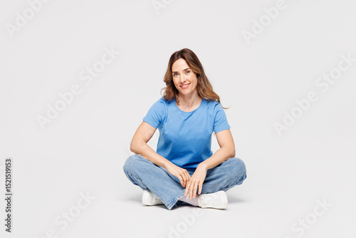 Fotografie Full body young smiling happy cheerful fun Caucasian woman wears blue t-shirt casual clothes sit looking camera isolated on plain solid white color wall background studio portrait
