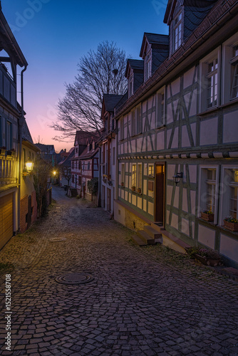Fototapeta Naklejka Na Ścianę i Meble -  A small alley with lanterns and half-timbered houses at dusk in Idstein in the Taunus region