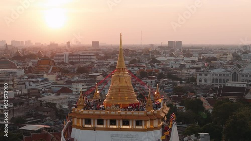 Golden mount temple above bangkok skyline during sunset, capturing crowds of tourists exploring religious landmark with panoramic city views, Thailand.