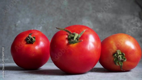 Closeup of hand picking red tomatoes on gray background