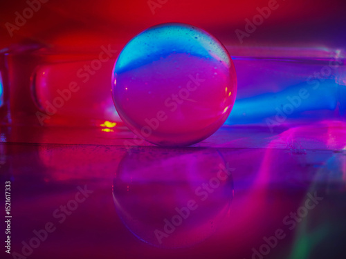 A clear glass ball is sitting on a pedestal. Colorful background. Abstract graphic background. Light effect. Planet in a space mood and feel.